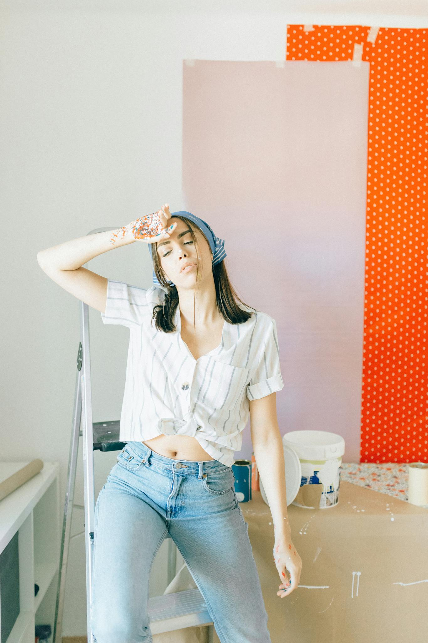 A young woman taking a break from wallpapering a room, looking stylish and relaxed.